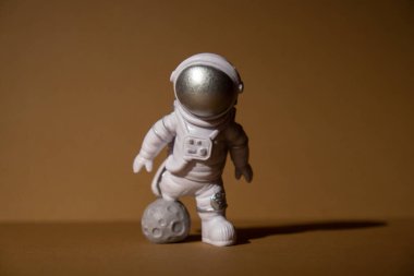 Plastic toy figure astronaut on beige neutral background Copy space. Concept of out of earth travel, private spaceman commercial flights. Space missions and Sustainability