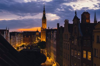 Gdansk 'taki güzel eski kasaba, Polonya' nın alacakaranlığında. Tarih merkezi Dluga Caddesi 'nin penceresinden ve belediye binasının mimari binası St Mary Bazilika' daki güneş batımı gece manzarası. Seyahat cazibesi