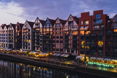 Gdansk 'ta eski bir kasaba, Polonya' nın alacakaranlığında. Gdansk Place 'de kalıp Motlawa nehri üzerindeki Wyspa Spichrzow Travel' de yemek yemek için yeni modern mimari binaların penceresinden gün batımını izliyoruz.