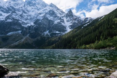 Morskie Oko lake Snowy Mountain Hut in Polish Tatry mountains, Zakopane, Poland. Beautiful green hills and mountains in dark clouds and reflection on the lake Morskie Oko lake. Travel tourist