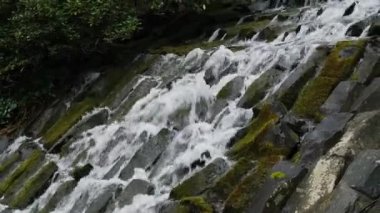 Akan şelalenin yavaş çekim görüntüleri suyun hareketini gösteriyor. Dağ şelalesi nehirlerin ve derelerin çağlayan kayalarının üzerine su döker. Ekosisteme ve yenilenebilir enerjiye saygı