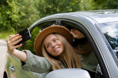 Gülümseyen bir kadın, arabasının camından cep telefonuyla video görüşmesi yapıyor. Hafta sonları yerel solo seyahat. Genç gezgin ormanda özgürlüğünü keşfediyor ve selfie çekiyor. Birliktelik