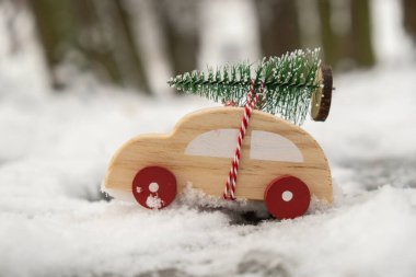 Karda Noel ağacı taşıyan ahşap bir araba. Karlı arazide oyuncak araba için uzayı kopyala. Mutlu Noeller ve mutlu yıllar konsepti. Kış geliyor. Tebrik kartı.