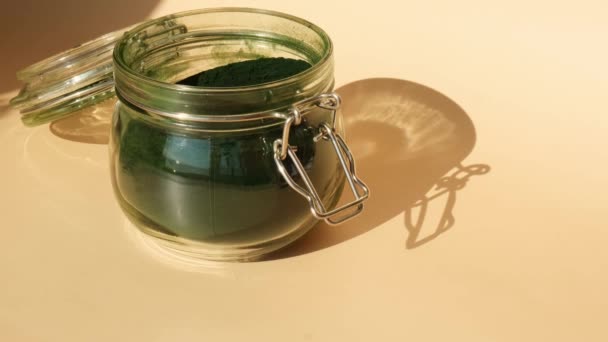 木のスプーンが付いているガラス瓶の有機的な青緑藻の藻のスピルリナの粉の食糧 スピルリナクロレラの健康上の利点 ダイエットするためのビタミンとミネラル デトックス栄養補助食品 海藻スーパーフードコンセプト — ストック動画