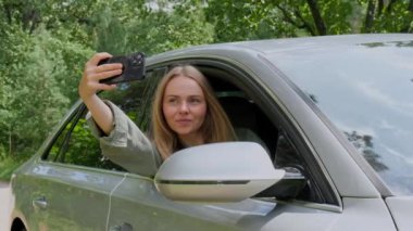 Gülümseyen bir kadın, arabasının camından cep telefonuyla video görüşmesi yapıyor. Hafta sonları yerel solo seyahat. Genç gezgin ormanda özgürlüğünü keşfediyor ve selfie çekiyor. Birliktelik