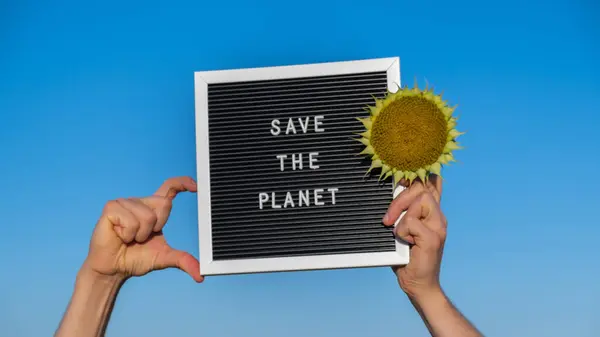 サンフラワーフィールドの背景に黒板にテキスト付きの抗議者の手 リサイクルコンセプトを削減する 自然への抗議 気候ストライキ 地球に対するボランティア抗議 — ストック写真