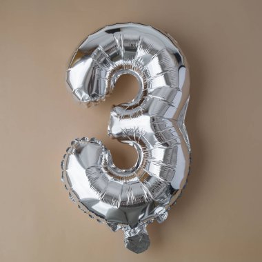 Bej renksiz arkaplanda 3 adet metalik balon. Kutlama kartı gümüş folyo balon numarası Mutlu yıllar tatil konsepti. Uzayı metin için kopyala. Kutlama partisi dekorasyonu.