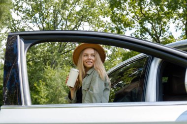 Sarışın kadın arabanın yanında durdu ve kahve ya da çay içmek için tekrar kullanılabilir kupaya geçti. Geri dönüşüm sıfır atık kavramını reddet. Genç turistler yerel seyahatleri keşfederek samimi anlar yaşarlar. Sorumlu