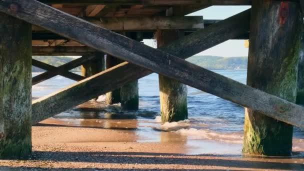 バックグラウンドデザインの木製ピアの下の嵐の海の波 海の波を吹き飛ばして走るシーケープ グダニスクポーランドのサンディビーチ休暇 — ストック動画