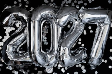 Koyu siyah arka planda konfeti olan 2027 yılınız kutlu olsun. Gümüş folyo balonları Noel tatili konseptini temsil ediyor. Kutlama partisi dekorasyonu.