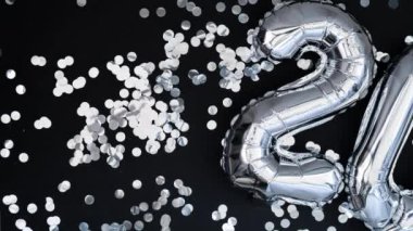 Yeni yılın kutlu olsun siyah arka planda konfetileri olan 2024 metalik balonları. Gümüş folyo balonları Noel tatili konseptini temsil ediyor. Kutlama partisi. Tebrikler.