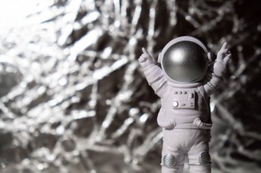Plastic toy figure astronaut on silver background Copy space. Concept of out of earth travel, private spaceman commercial flights. Space missions and Sustainability