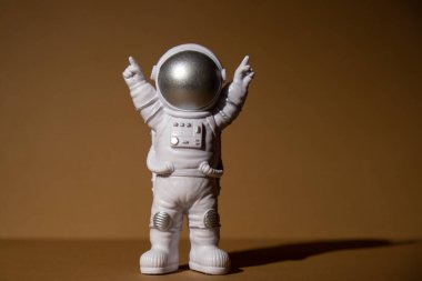 Plastic toy figure astronaut on beige neutral background Copy space. Concept of out of earth travel, private spaceman commercial flights. Space missions and Sustainability