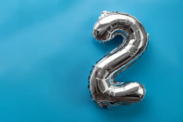 2 two metallic balloon isolated on blue background. Greeting card silver foil balloon number Happy birthday holiday concept. Copy space for text. Celebration party congratulation decoration