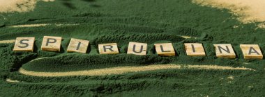 Alg süper yiyecek tozunun arka planında SPIRULINA klorellası olan tahta bloklar. Sağlıklı fayda desteği ve vegan antioksidan sağlıklı yeme konsepti 