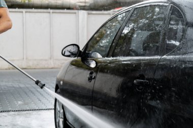 Dokunulmaz araba yıkamada lüks siyah araba yıkama. Arabanın detaylarını temizliyorum. Köpüklü araba yıkama ve yüksek basınçlı su. Kentsel çevrede temizlik ve düzen