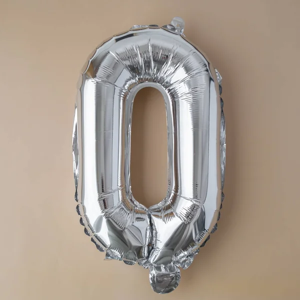 0 ZERO metallic balloon on beige neutral background. Greeting card silver foil balloon number Happy birthday holiday concept. Copy space for text. Celebration party congratulation decoration