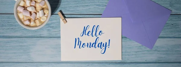 HELLO MONDAY blue monday concept text blue envelope with white cup of coffee and marshmallows on wooden background. The most depressing day of the year in January. Day commit suicide and depression motivation sign. Top view, flat lay