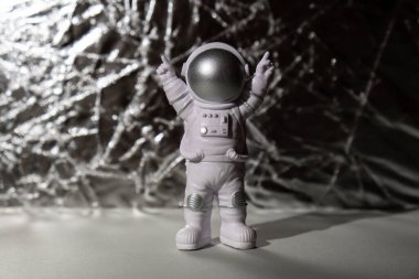 Plastic toy figure astronaut on silver background Copy space. Concept of out of earth travel, private spaceman commercial flights. Space missions and Sustainability