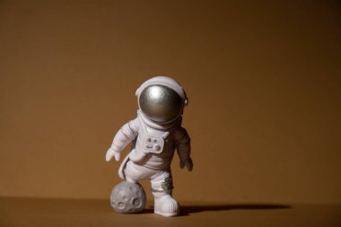 Plastic toy figure astronaut on beige neutral background Copy space. Concept of out of earth travel, private spaceman commercial flights. Space missions and Sustainability