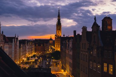 Gdansk 'taki güzel eski kasaba, Polonya' nın alacakaranlığında. Tarih merkezi Dluga Caddesi 'nin penceresinden ve belediye binasının mimari binası St Mary Bazilika' daki güneş batımı gece manzarası. Seyahat yeri turizm merkezi Dramatik bir gökyüzü 