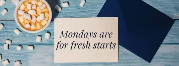MONDAYS ARE FOR FRESH STARTS concept text Banner blue envelope with white cup of coffee and marshmallows on wooden background. The most depressing day of the year in January. Day commit suicide and depression motivation sign. Top view, flat lay