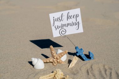 Çapa kağıt tutacağındaki kağıt tebrik kartı ve deniz yıldızı deniz kabuğu yaz tatili dekoru üzerinde yüzmeye devam et. Kumsalın güneş kıyısı. Tatil konsepti kartpostalı. Kaçmak Seyahat İş Konsepti