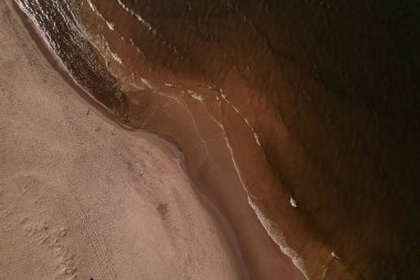 Dalgaların, deniz kıyılarının insansız hava görüntüsü. Kumsallar ve kumullar, sakin deniz dalgaları insansız hava aracıyla ele geçirilen doğa manzarası. Polonya 'da turizm
