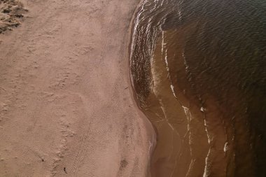 Dalgaların, deniz kıyılarının insansız hava görüntüsü. Kumsallar ve kumullar, sakin deniz dalgaları insansız hava aracıyla ele geçirilen doğa manzarası. Polonya 'da turizm