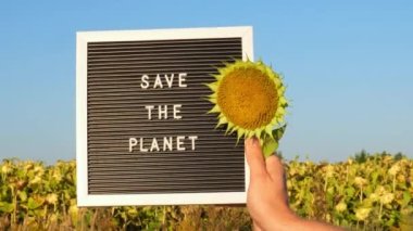 Bayrak mesajıyla tanınmayan kişi güneşli bir günde Ayçiçeği tarlasında gezegeni kurtardı. Dünya 'yı imzala. Ekoloji ve çevre aktivizmi kavramı küresel ısınmayı durdurur. Bastır yeşil