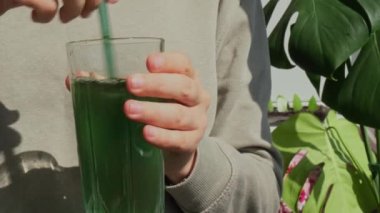 Tarafsız bej arka planda doğal organik yeşil spirulina alg tozu içen tanınmamış bir kadın. Chlorella deniz yosunu vejetaryen süper yemek kokteylleri smoothie takviye kaynağı ve detoks içeceği.