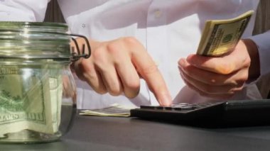 Hesap makinesindeki dolar banknotlarını saydıktan sonra Bitcoin para dijital altını gösteren usta eller. El ele tutuşup tanınmaz hale geliyor. Kazanılan ticaret grafikleri büyümesi