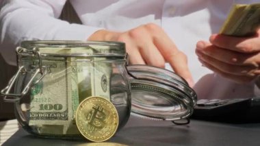 Bitcoin dijital altın. Uzman tüccarların elinde cam kavanozdan gelen dolar banknotlarını sayıyor. El ele tutuşup tanınmaz hale geliyor. Kazanılan ticaret grafikleri büyüme Kripto para birimi