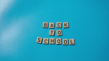 Yaratıcı mavi arka planda ahşap bloklar ve kırtasiye malzemeleriyle birlikte ahşap bloklar üzerine yazılmış okul mesajına geri dönüş zamanı. Öğrenciler ve öğretmenler için eğitici karşılama duyurusu