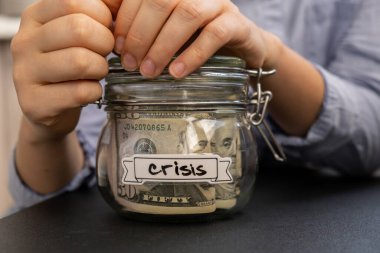 Cam kavanoz dolusu Amerikan Doları 'nı elinde tutan kadın. CRISIS yazılı nakit para. Hazırlık para tasarrufu. Orta karar tüketim ve ekonomi. Para toplama