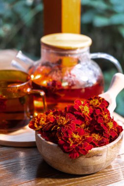 Marigold çayı yeşil bahçe arka planında masada hala hayat devam ediyor. Sağlıklı sıcak içecek faydaları. Doğal organik aromatik içecekler. Çay için ev yapımı bağışıklık güçlendirici otlar. Sonbahar kış ısınması