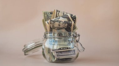 Bir dolarlık banknot cam kavanozda para biriktiriyor. Tüketim ve ekonomi para topluyor. Bahşiş. İş, finans, tasarruf, bankacılık ve insan konsepti. Ekstra para, pasif 