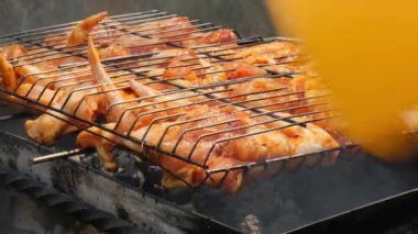 Barbeküde ızgara ızgarada kızarmış tavuk. Baharat taze ızgara tavuk kanatlarına dökülüyor. Yaz partisi yemekleri. Barbekü Sulu ızgara ızgarada kızarmış tavuk budu. 