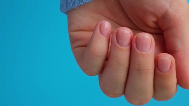 女人修剪过的手 时髦的米黄色指甲 用蓝色背景的蓝色毛衣把女性手的指甲修整好 冬季或秋季风格的指甲设计理念 美容疗法 — 图库视频影像