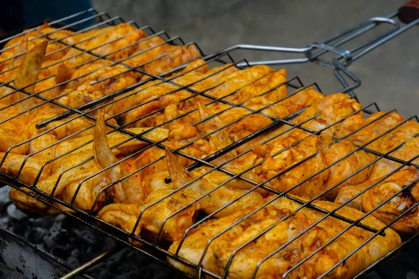 Barbeküde ızgara ızgarada kızarmış tavuk. Baharat taze ızgara tavuk kanatlarına dökülüyor. Yaz partisi yemekleri. Barbekü Sulu ızgara ızgarada kızarmış tavuk budu. 