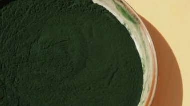 Dönen organik mavi-yeşil yosun tabaktaki spirulina tozu. Spiulina Klorella 'nın sağlık yararları. Diyet için vitamin ve mineraller. Detox diyet takviyesi. Deniz yosunu süper yiyecek kavramı.