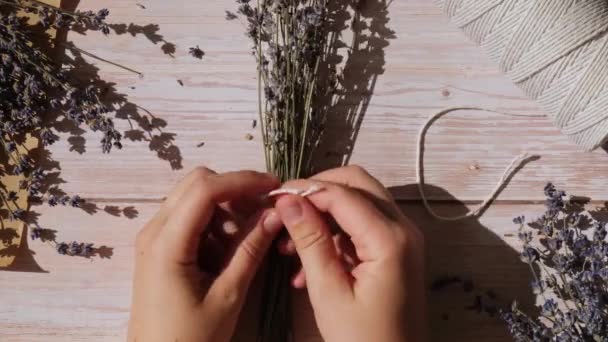 ドライラベンダーの花束を作るプロセスのトップビューフラットレイ コットンロープ ハサミ 女性は自家製ハーブブブーケをする 冬のための準備 — ストック動画