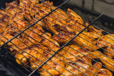 Barbeküde ızgara ızgarada kızarmış tavuk. Baharat taze ızgara tavuk kanatlarına dökülüyor. Yaz partisi yemekleri. Barbekü Sulu ızgara ızgarada kızarmış tavuk budu. 