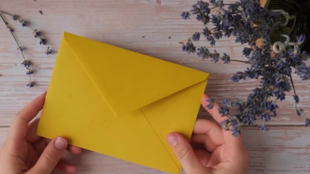 黄色い封筒から紙のカードノートを取る女性の手 ラベンダー フラワー トップビュー フラットレイ 精神的な健康の概念 セルフケア マインドフルネス — ストック動画