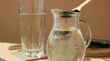 Doğal yeşil spirulina alg tozunu doğal bej arka planda su içeceğine ekleyin. Chlorella deniz yosunu vejetaryen süper yemek kokteylleri smoothie takviye kaynağı ve detoks içeceği. Yenilikçi