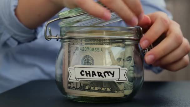 女性的手在装有美元钞票的玻璃瓶中增加了钱 在罐子前面的绿色转录 为今后的不安全背景管理个人财政额外收入 — 图库视频影像