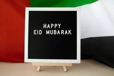 İleti metni Mutlu EID MUBARAK - Arka plan konseptinde BAE bayrağı sallayarak mutlu tatiller. Tebrik kartı reklamı. Müslüman Ramazan Bayramı kutsanmış ay resmi bayramıdır. Vatanseverlik