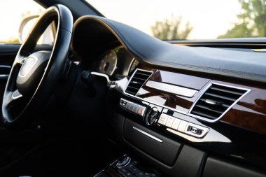 Günbatımında otoyolda modern lüks arabanın direksiyonu ve iç mekanı. Multimedya menü kontrol sistemi panelinin ayrıntıları, içerideki gösterge paneli. Prestijli spor otomobil. Seçici odak