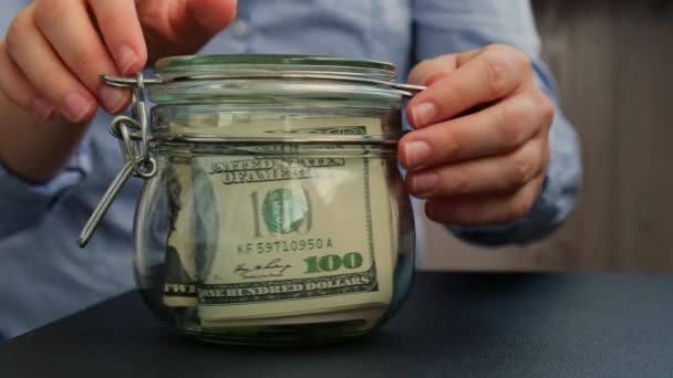 Onherkenbare Vrouw Zet Spaargeld Glazen Pot Gevuld Met Dollars Bankbiljetten — Stockvideo