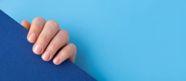 Pastel yumuşaklığı mavi arka planda manikürlü tırnaklar. Yeni manikürünü Pastel Palet renginde gösteren şablon fotokopi uzayı kadını oluşturun. Basitlik dekoru Taze bahar titreşimleri Dünya renginde nötr